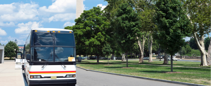 Bus driving down the road in front of the Washington monument
