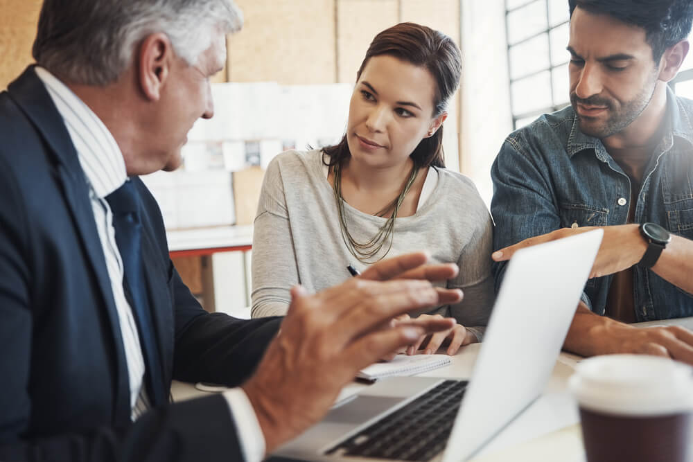 A woman and man work with a lawyer to appeal a workers' comp denial.