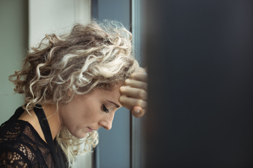 upset businesswoman leaning against window