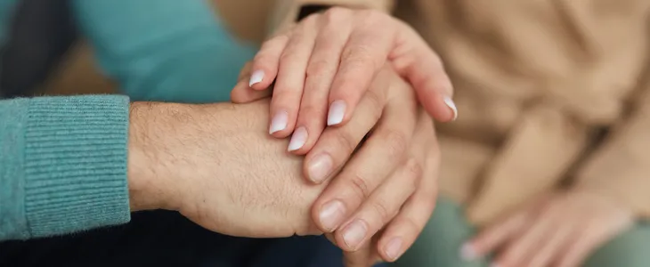 Wife putting her hand on a husband's hand to comfort him
